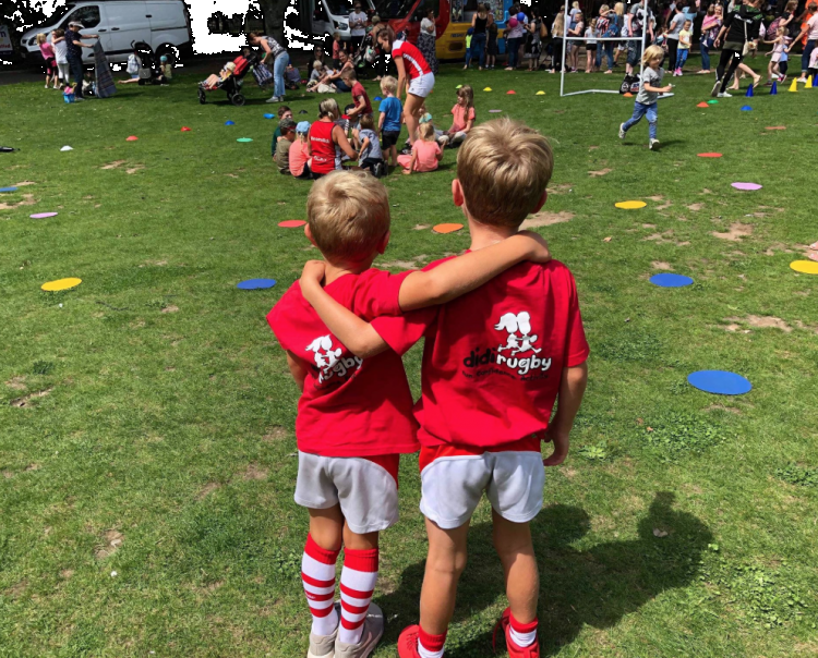 Two boys with didi rugby shirts on watch a game