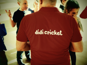 Children talk to a man wearing a didi cricket tee-shirt