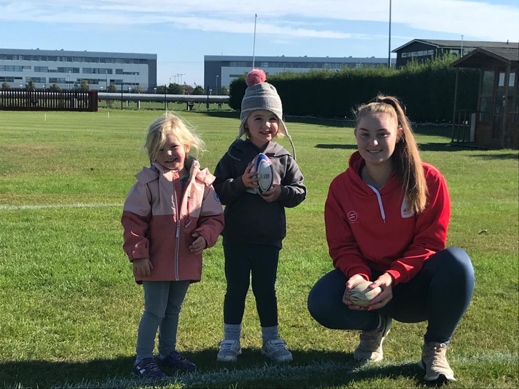 didi rugby Reading coach and keen rugby player Caitlin Clark smiles next to two happy children