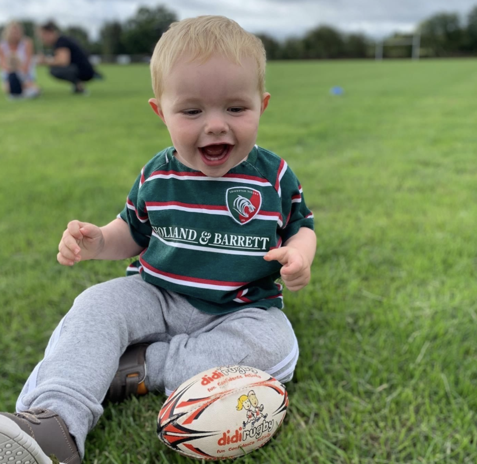 A young boy in a Leicester Tigers top plays with a didi rugby ball