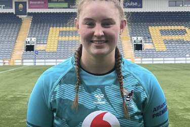 A lady rugby player called Caitlin Clark smiles while wearing a blue sports top