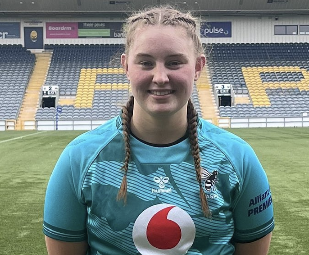 A lady rugby player called Caitlin Clark smiles while wearing a blue sports top