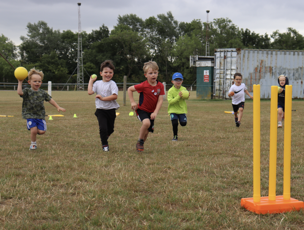 Children throwing cricket balls at stumps