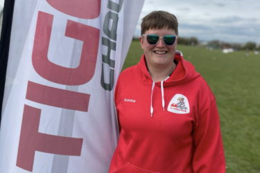 didi rugby Sandbach coach Ros Wiggins smiles wearing a red didi rugby hoodie and sunglasses
